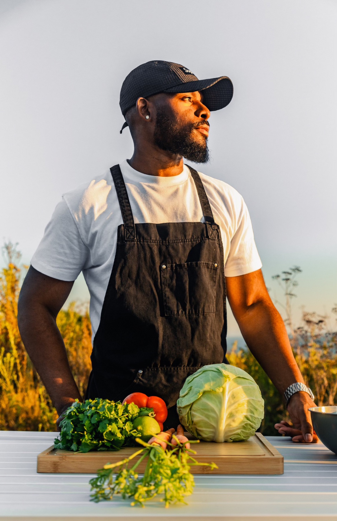 Davon Moseley in a black apron at a golden-hour field kitchen