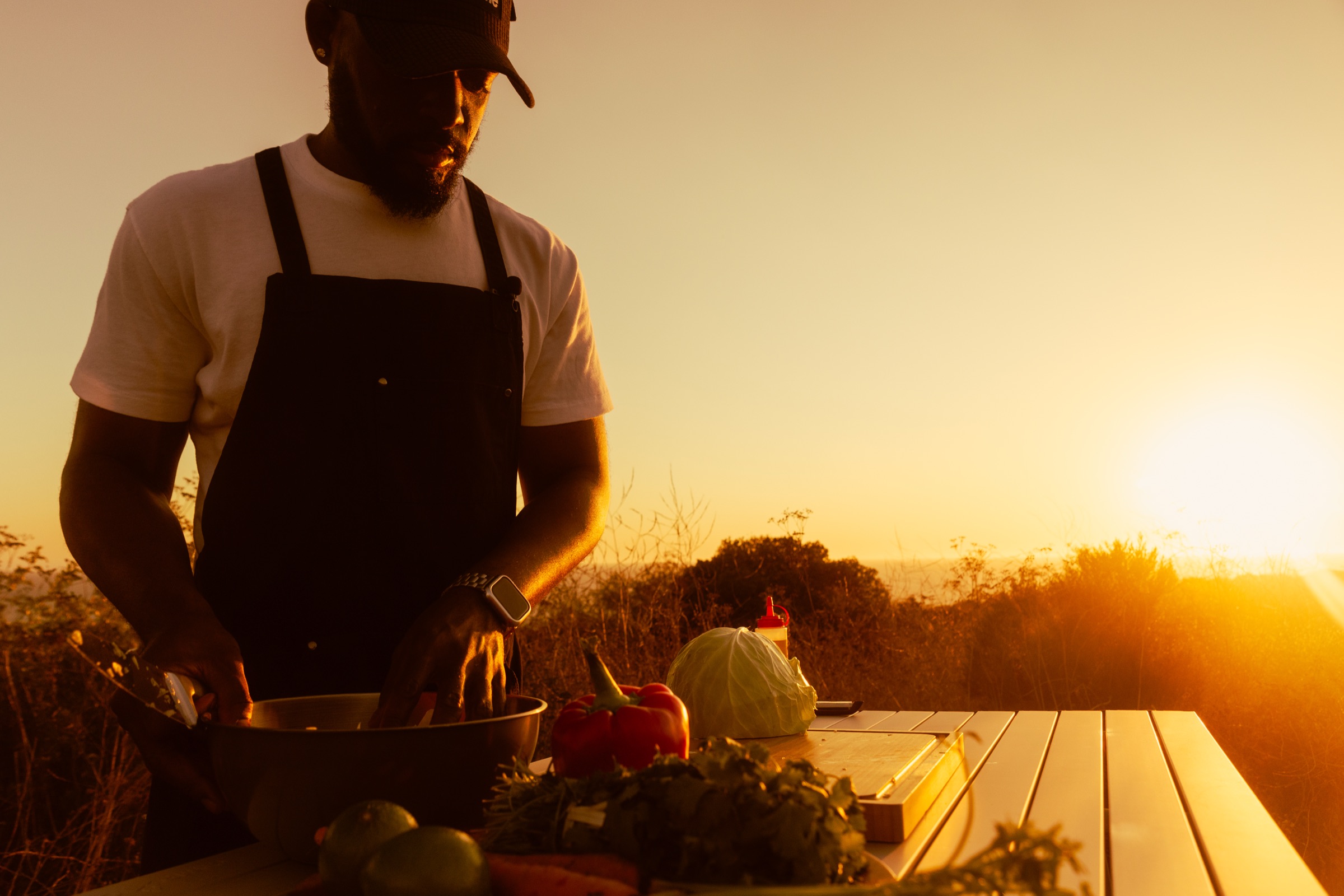 Davon prepping vegetables outdoors at sunset