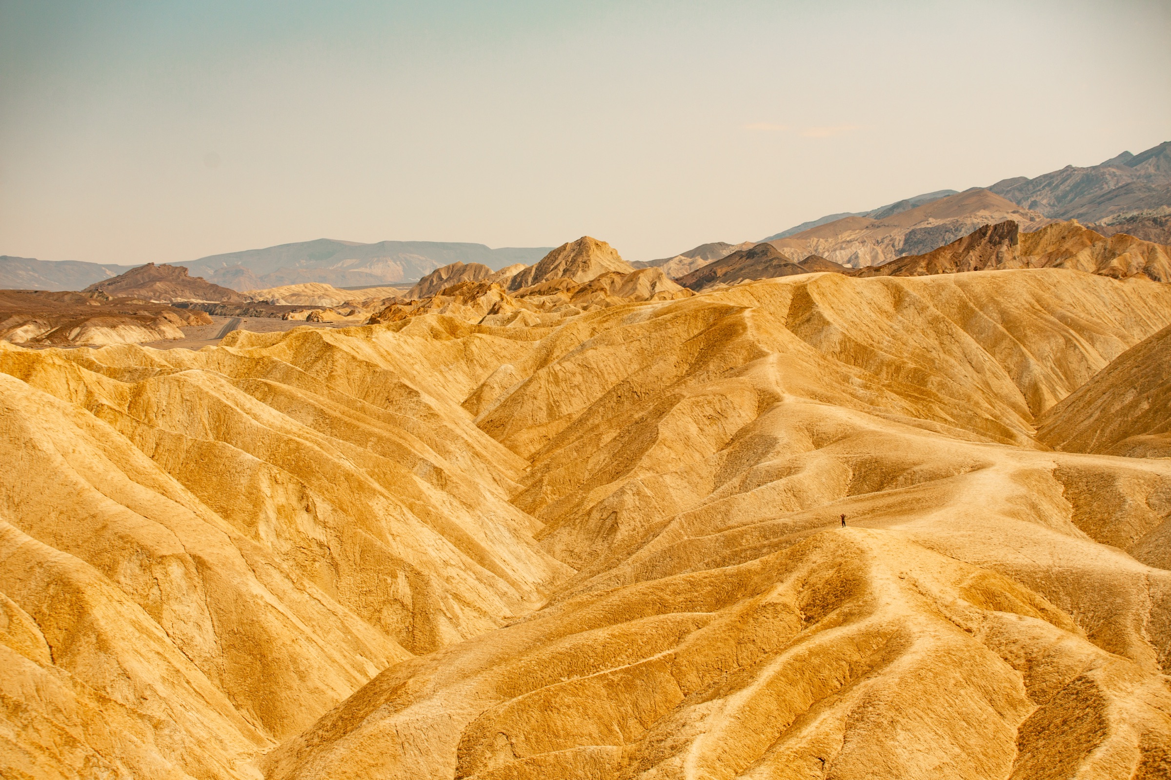 Golden folded badlands under a wide pale sky