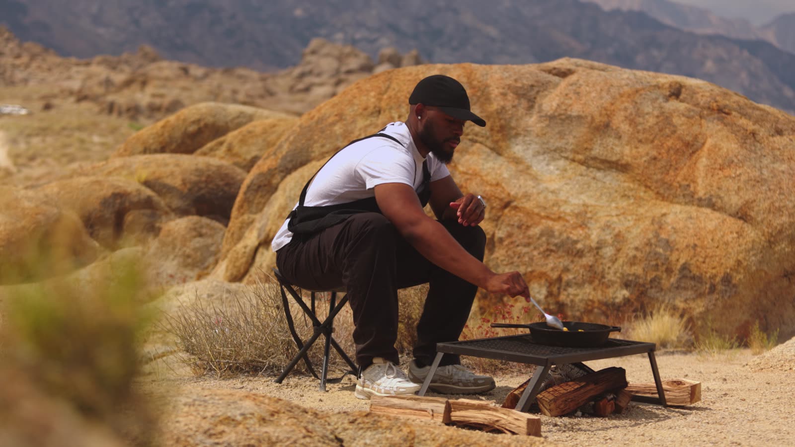 Davon cooking over a camp fire grate among golden boulders
